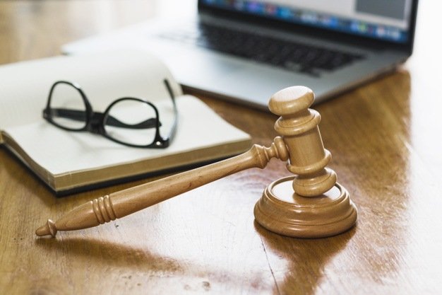 close-up-gavel-book-laptop-spectacles-wooden-desk_23-2147876792