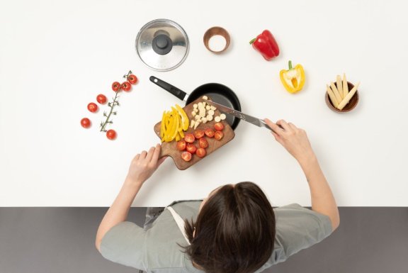a-young-woman-adding-vegetables-to-a-saucepan.