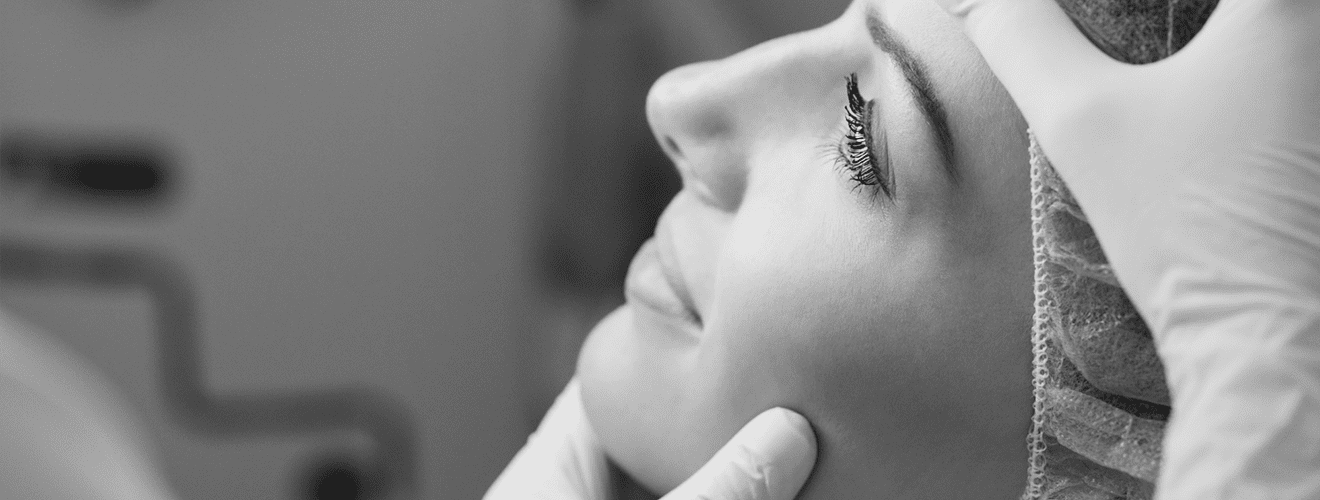 Close-up of doctor examining a patient's cheek and jawline area before a facial aesthetic procedure.