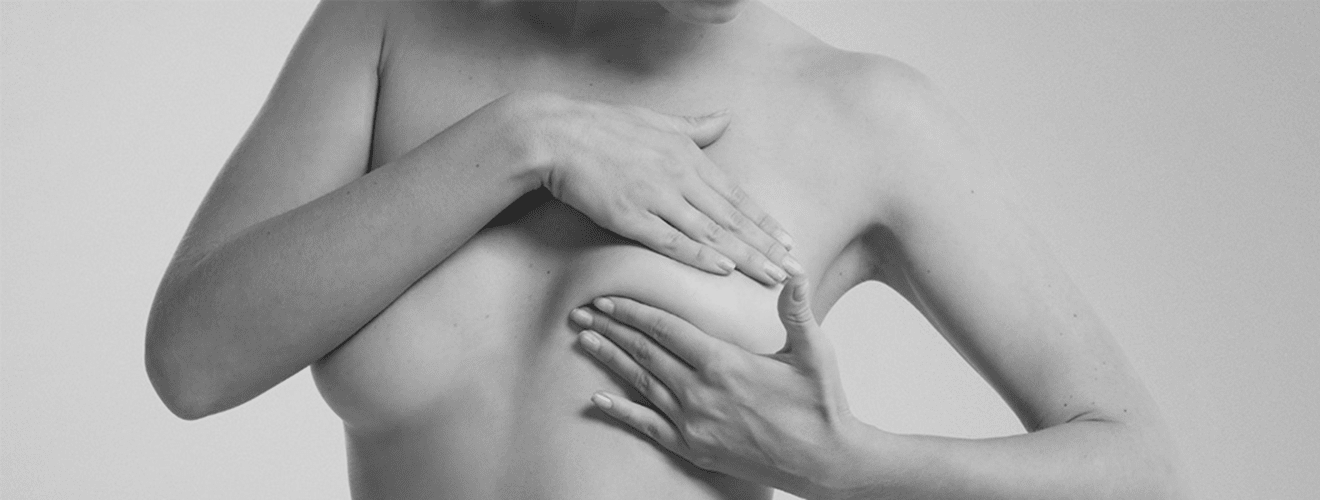 Woman gently touching her breast, symbolizing integration and healing during or after breast reconstruction surgery.