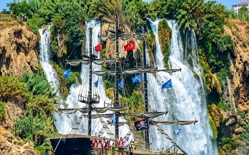 Pirate ship with guests on deck anchored beneath the Düden Waterfall near Lara