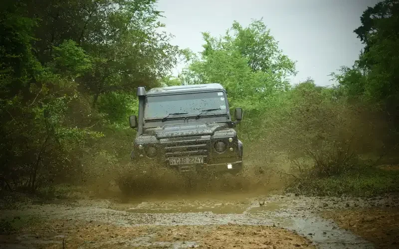 Land Rover Defender fährt durch Schlamm auf einer Waldpiste