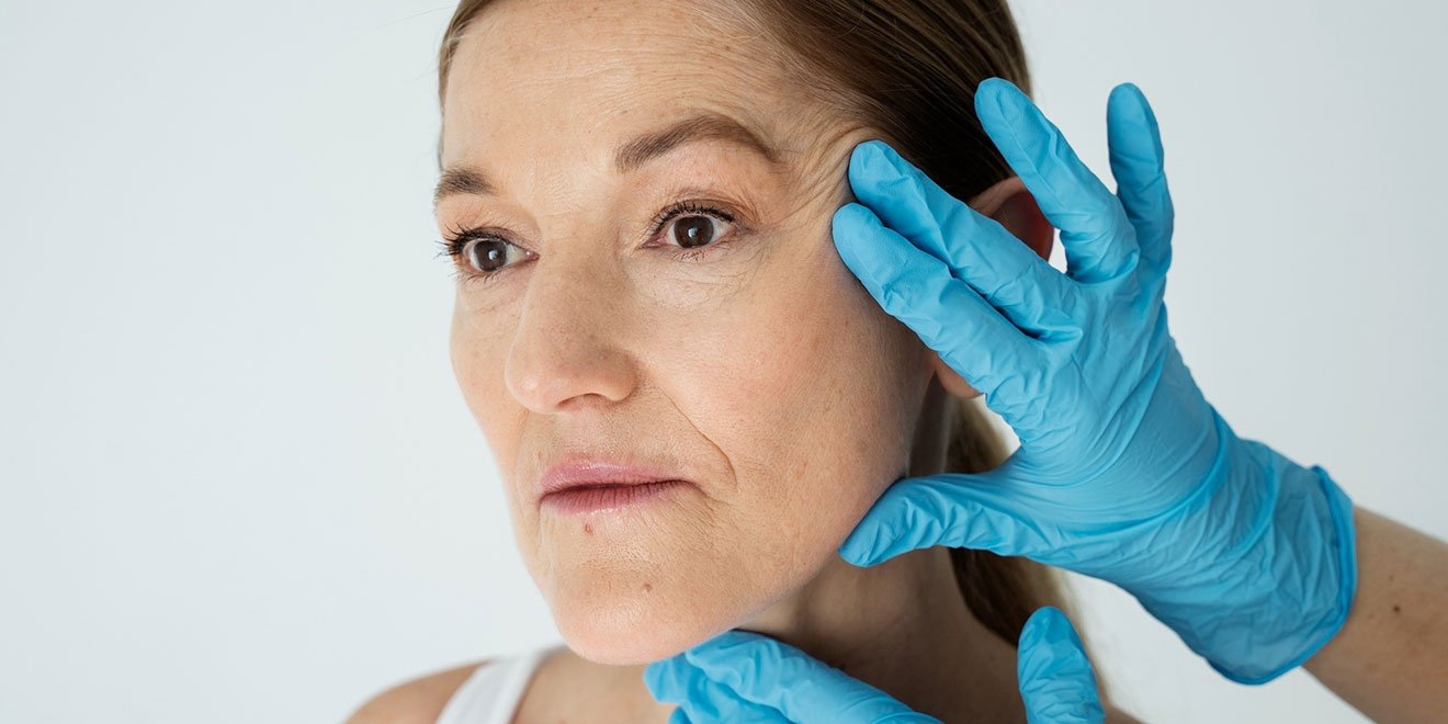 An expert assessing a patient's facial sagging and wrinkles for Deep Plane Facelift vs SMAS lift techniques