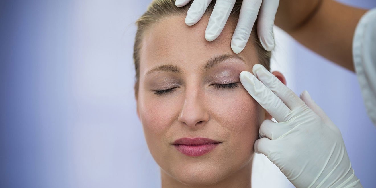 Doctor examining a patient's upper eyelid drooping and lower eyelid bags.